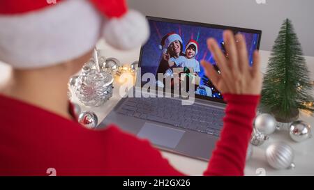 Une femme caucasienne appelle sa famille en ligne sur un ordinateur portable et souhaite un Joyeux Noël. Réunion à distance de la nouvelle année Banque D'Images