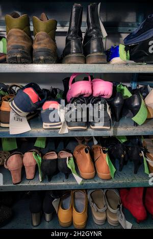 Chaussures dans l'atelier de réparation, empilées et triées. Banque D'Images