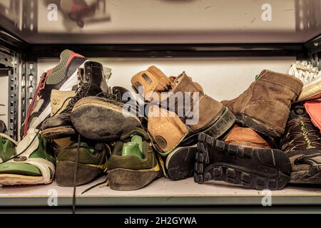 Chaussures dans un atelier de réparation, empilées et désordonnées. Banque D'Images