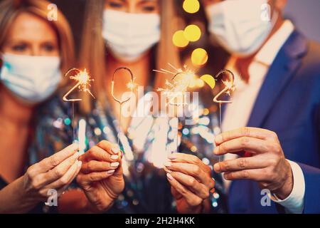 De beaux jeunes amis dans des masques s'amuser à la fête de la Saint-Sylvestre 2022 Banque D'Images