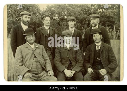 Magnifique carte victorienne originale d'un groupe de 7 personnes de caractère, de bonne recherche, de bons messieurs humoristés, de divers âges, dans une posture tout à fait informelle et détendue pour l'époque.Ces hommes sont de classe moyenne car ils portent des montres de poche qui étaient un symbole de statut cher à l'époque et les photos montrent les hommes montrant les chaînes de montre avec des vestes de costume ouvertes, ils sont assis à l'extérieur dans un jardin.Il y a de bons exemples de mode.Tous portent des « manteaux de sac » ou des « manteaux de ville » de laine et de tweed, des chapeaux de bowling, des casquettes plates.L'homme portly porte un trou de bouton de rose de soie. Vers 1885, Royaume-Uni Banque D'Images