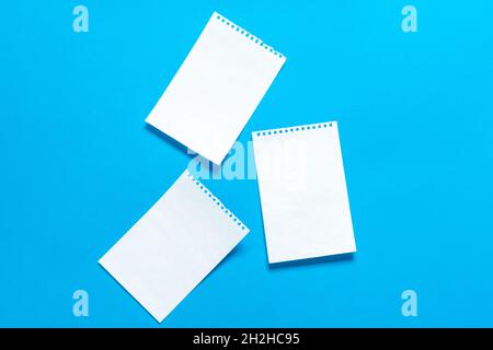 Feuilles de papier blanches déchirées d'un bloc-notes sur fond bleu vif, placez-les pour votre texte.Trois affiches vierges blanches isolées sur bl Banque D'Images
