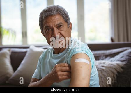 Portrait de l'homme aîné biracial montrant un bandage sur le bras après la vaccination des Covid Banque D'Images