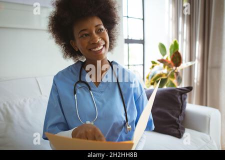 Une femme afro-américaine souriante tient des documents chez elle Banque D'Images