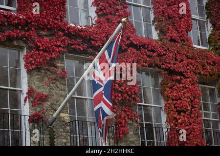 Union Jack a vu voler sur un mât de drapeau sur un bâtiment au Royaume-Uni, sur fond de feuilles d'automne. Banque D'Images