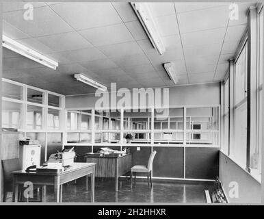 Bureau, Chester-le-Street, County Durham, 1956-1969.Une longue vue des espaces de vestibules de bureau, probablement depuis l'intérieur de AEC Earthmoving Equipment, à Chester-le-Street, dans le comté de Durham, montrant un homme assis dans un stand central, avec deux bureaux vides et une machine à écrire dans la zone de travail avant.Le numéro d'archive alternatif M4839 fait référence au numéro donné par les photographes Philipson. Banque D'Images