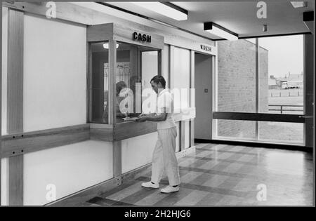 Piscine Blyth, Blyth, Northumberland, 1960-1980.Un comptoir-caisse et un comptoir d'entrée, avec une porte dirigée vers la droite, peut-être dans la zone de réception de la piscine Blyth, Northumberland, montrant un homme debout sur le côté public du comptoir, parlant à une femme.Une légende manuscrite au verso de l'image indique « C.C.S.451/12A."On ne sait pas à qui, ou à quoi, cela se rapporte, mais il s'agit peut-être d'un autre photographe et de son propre code de référence d'image. Banque D'Images