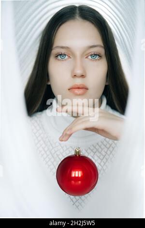 Fille en dôme blanc avec boule de Noël rouge Banque D'Images