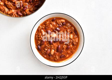 Ragoût de haricots avec du bœuf haché, du piment jalapeno et du bacon dans un bol sur fond de pierre légère.Vue de dessus, plan d'installation, gros plan Banque D'Images