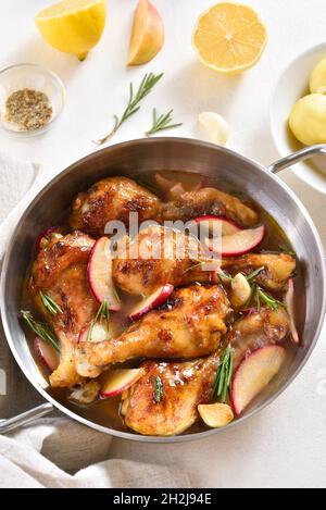 Pilons de poulet cuits avec des pommes et des herbes dans une casserole.Vue rapprochée Banque D'Images