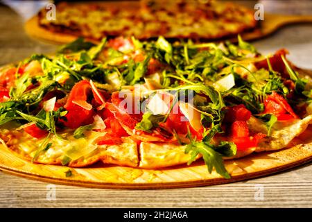 Flamkuchen est une spécialité croustillante d'Alsace, généralement avec une garniture de crème aigre, d'oignons et de bacon.Il s'agit d'une variation avec l'arugula et les tomates. Banque D'Images