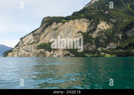 Il y a une colline rocheuse qui est visible depuis le lac de Lucerne.Il y a une route qui a été creusée dans le rocher et qui longe maintenant le côté de la falaise. Banque D'Images