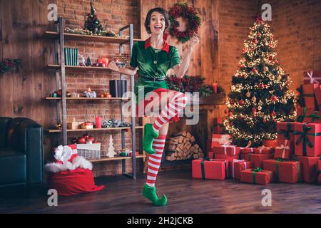 Photo pleine longueur de jeune femme positive elf noël bonne humeur gagnant célébrer profiter à l'intérieur de la maison maison Banque D'Images