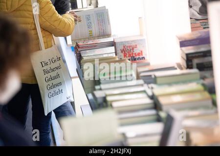 22 octobre 2021, Hessen, Francfort-sur-le-main : une femme se trouve à travers un livre au stand du groupe d'édition Penguin Random House lors du premier jour de visite de la Foire du livre de Francfort 2021.Après une foire provoquée par une pandémie sans visiteurs en 2020, les visiteurs sont de nouveau admis sous restrictions cette année.La foire aura lieu du 20 au 24 octobre 2021.Photo: Sebastian Gollnow/dpa Banque D'Images