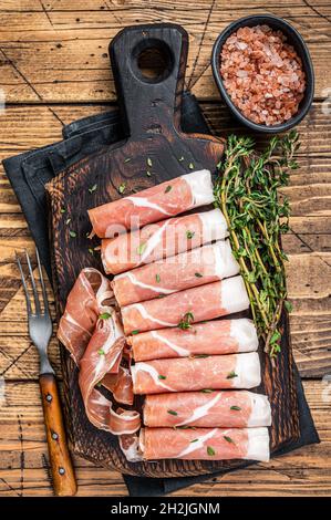 Prosciutto crudo jambon de parme sec sur une planche à découper en bois avec thym. fond en bois. Vue de dessus Banque D'Images