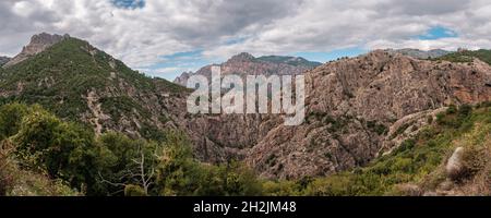 Vue panoramique sur les montagnes rocheuses du centre de la Corse avec une route au loin Banque D'Images