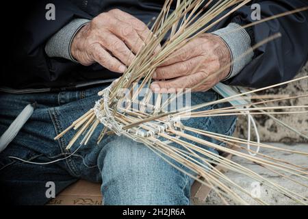 Les mains d'un ancien pêcheur sicilien serpentent un traditionnel 'nassa' (piège à poisson) dans la ville de Milazzo en Sicile Banque D'Images