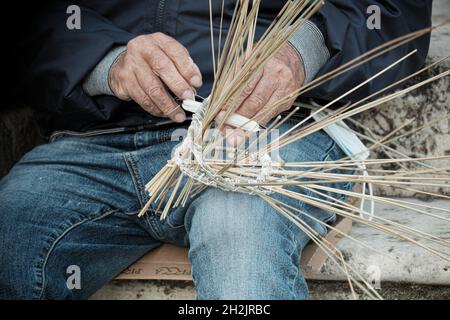 Les mains d'un ancien pêcheur sicilien serpentent un traditionnel 'nassa' (piège à poisson) dans la ville de Milazzo en Sicile Banque D'Images