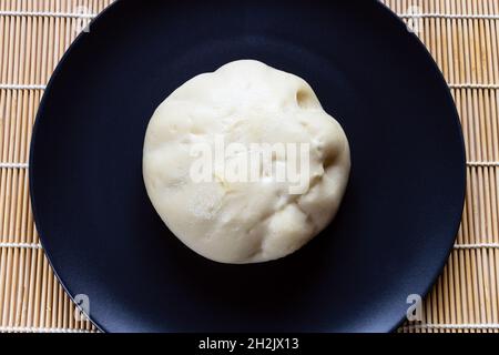 Vue de dessus de Banh Bao cuit à la vapeur, petit pain vietnamien salé, sur une assiette noire Banque D'Images