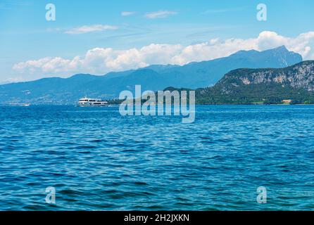 Ferry en bateau dans la navigation sur le lac de Garde, promontoire de San Vigilio et le sommet de montagne de Monte Pizzocolo.Province de Vérone, Vénétie, Lombardie, Italie. Banque D'Images