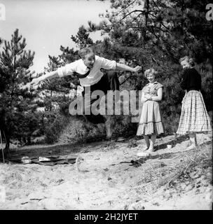 Jeune homme impressant les filles en sautant dans l'air Grande-Bretagne 1950 Banque D'Images