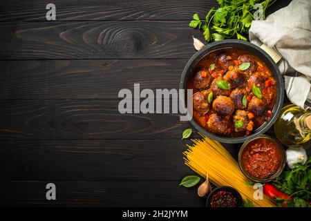 Boulettes de viande en sauce tomate et pâtes sur table en bois sombre. Banque D'Images