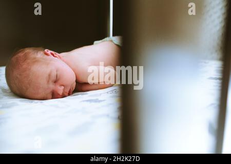 Un bébé garçon dormant sur son ventre dans un berceau Banque D'Images