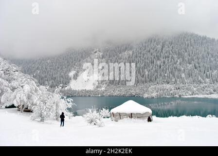 Vue depuis une distance d'homme près du lac de montagne, sur la neige en hiver Banque D'Images