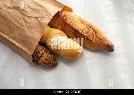 baguettes multigrains de seigle, de blé dans un sac de papier sur nappe blanche Banque D'Images