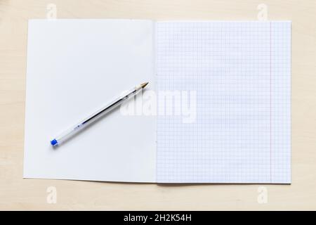 vue de dessus du stylo et de la première page vierge du carnet scolaire ouvert avec des feuilles carrées avec marges sur panneau en bois brun clair Banque D'Images