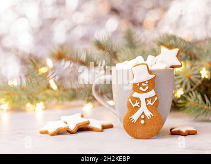 Mignon pain d'épice Snowman cookie devant une tasse de chocolat chaud avec guimauves.Arrière-plan joli bokeh. Banque D'Images