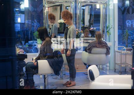 LONDRES, ANGLETERRE - NOVEMBRE 19 2017: REDHEAD Cully Girl coiffeur regarde dans le miroir de son client avant une coupe de cheveux Banque D'Images