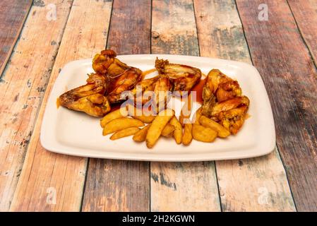 Délicieux service d'ailes de poulet frites avec sauce barbecue et frites coupées en quartiers Banque D'Images