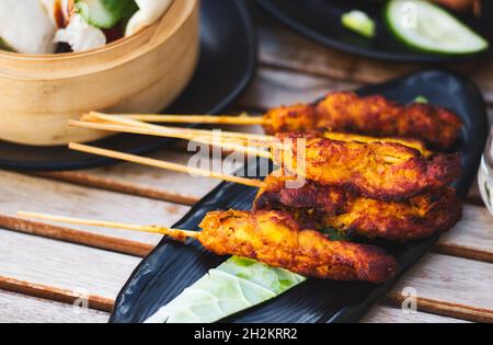 Morceaux de satay de poulet sur des brochettes en bois sur une assiette Banque D'Images