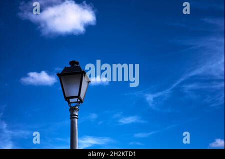 détail d'une lampe de rue en fer forgé contre un ciel bleu et nuageux Banque D'Images