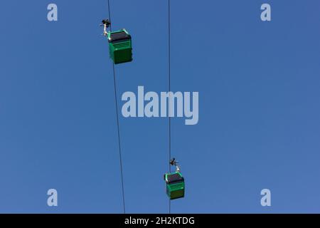 Téléphériques verts sur ciel bleu par en dessous.Concept d'attraction touristique Banque D'Images