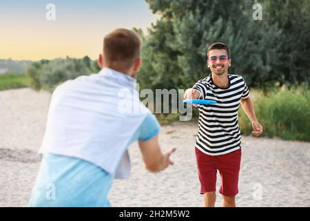 Jeunes hommes jouant au Frisbee sur la plage Banque D'Images