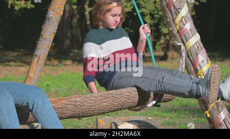 une adolescente fait une balançoire dans la nature avec sa mère par temps ensoleillé. Banque D'Images