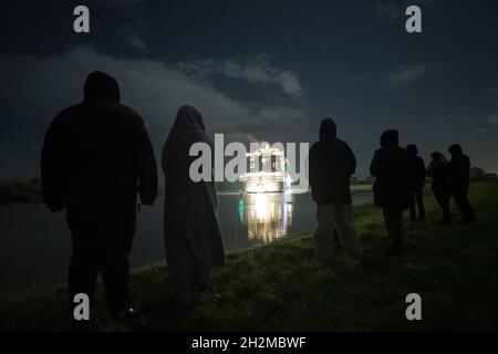 Papenburg, Allemagne.23 octobre 2021.Les spectateurs regardent le bateau de croisière 'Aidacosma' de 337 mètres de long remorqué par la rivière EMS la nuit.Le nouveau géant de croisière 'Aidacosma' a commencé son remorquage du chantier naval Meyer sur l'EMS à la mer du Nord.Credit: Mohssen Assanimoghaddam/dpa/Alay Live News Banque D'Images