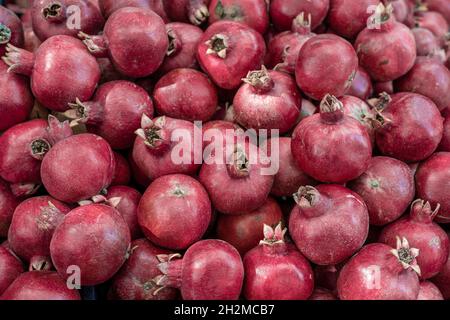 Grande pile de grenades sur le comptoir du marché des fruits.gros plan de lot de grenades rouges mûres avec des taches sur le comptoir du marché pour la vente ou la préparation o Banque D'Images