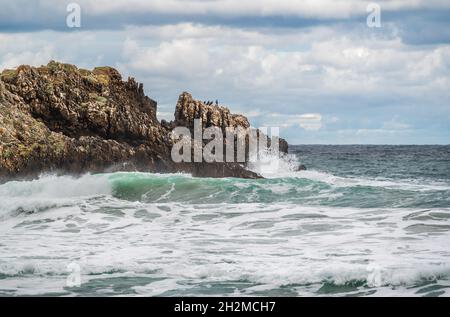 L'eau de l'océan éclabousse sur la plage de rochers avec de beaux couchers de soleil et des nuages.Vagues de mer éclaboussant sur la pierre au bord de la mer en hiver.Impact de la ligne de cils Sea Waves Banque D'Images