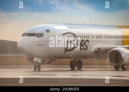 Avion jaune de la compagnie aérienne Bees sur le tablier.Boeing 737-800 UR-UBA avion de tourisme.Après la pluie et le lavage.Copier piste d'espace.Ukraine, Kiev - 19 mars 2021. Banque D'Images