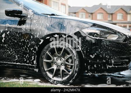 Voiture moderne recouverte de mousse.Lavage de voiture. Banque D'Images