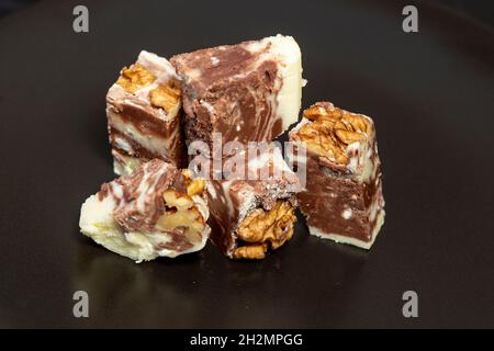 Caramel noir et blanc au chocolat avec noix, isolé sur fond noir.Bonbons pour Noël. Banque D'Images