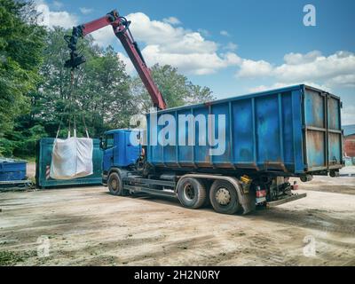 Grue de camion avec sac poubelle sur une cour de recyclage. Banque D'Images