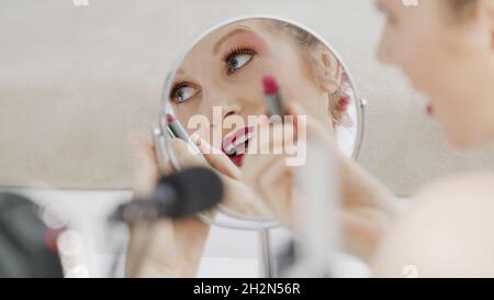 Sourire blond influenceur blogueur enregistrement vidéo tutoriel, tourné en gros plan dans le miroir, montre comment appliquer des cosmétiques de maquillage de lèvre.Femme vlogger makin Banque D'Images