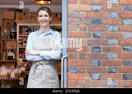 Portrait de la femme propriétaire debout à l'entrée de Delicatessen Food Boutique Banque D'Images