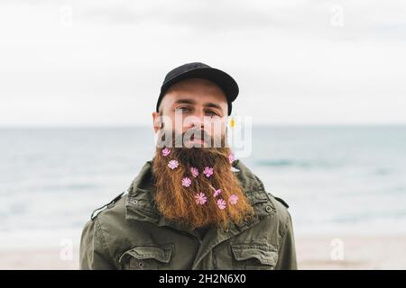 Un jeune homme taille basse porte des fleurs à la plage Banque D'Images