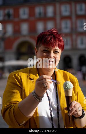 Femme mûre souriante mangeant de la crème glacée Banque D'Images