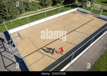 Sportif jouant au basket-ball avec une amie pendant la journée ensoleillée Banque D'Images